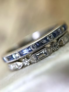 two wedding rings with blue and white diamonds on top of each other's bands