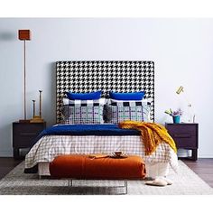 a bed with pillows and blankets on top of it next to a dresser in a bedroom