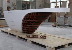 a large white sculpture sitting on top of a wooden pallet in a building under construction