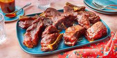 steaks on a blue platter with drinks and utensils in the background