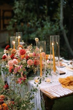 the table is set with candles and flowers in glass vases on top of it