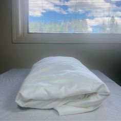 an unmade bed in front of a window