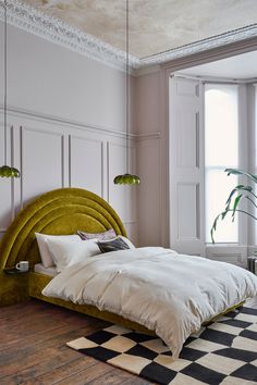 a bedroom with a large bed, checkered rug and potted plant in the corner