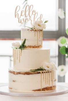 a wedding cake with gold drips and greenery