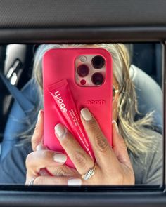 a woman taking a selfie with her cell phone in the back seat of a car