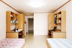 two beds in a room with wooden cabinets and desks next to eachother