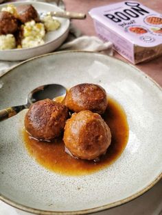 three meatballs covered in gravy on a plate next to a box of booze