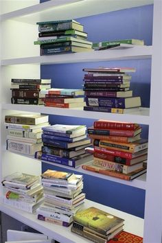 a book shelf filled with lots of books on top of white shelving unit shelves