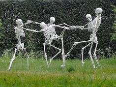 three skeletons dancing in the grass with their arms around each other's body and legs