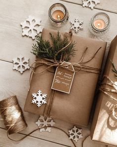 two wrapped presents on a table with candles and snowflakes