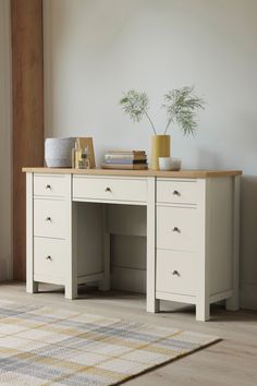 a white desk with two drawers and a potted plant on top