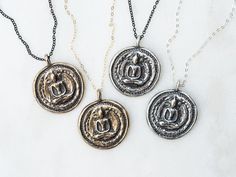 "Thai Buddha Coin Necklace These funky pendants will become your new favorite everyday piece of jewelry! They are modeled after an antique Buddha coin I've had for many years and have cherished. You can customize your necklace by choosing the pendant metal, chain color and length. All pendants are antiqued with a black patina to keep the antique and rustic feel. The original prototype was first carved out of bronze metal clay and then fired in a kiln until only solid metal remained. Each of thes Spiritual Hand Forged Medallion Necklaces, Spiritual Hand Forged Medallion Necklace, Black Spiritual Jewelry With Antique Finish, Spiritual Necklace With Antique Finish Round Pendant, Symbolic Soldered Medallion Necklaces, Spiritual Necklaces With Antique Finish Round Pendant, Spiritual Antique Finish Round Pendant Necklace, Symbolic Soldered Medallion Necklace, Symbolic Medallion Necklace With Soldered Details