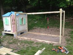 an outdoor play area with a wooden structure and tools on the ground next to it