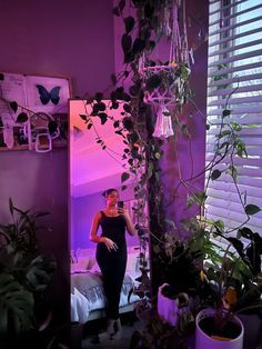 a woman standing in front of a mirror next to plants