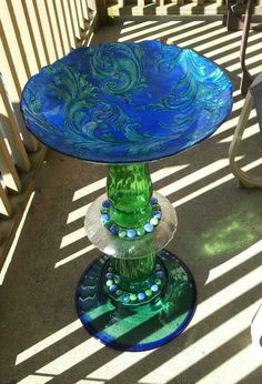 a green glass cake plate sitting on top of a metal stand with blue and green designs