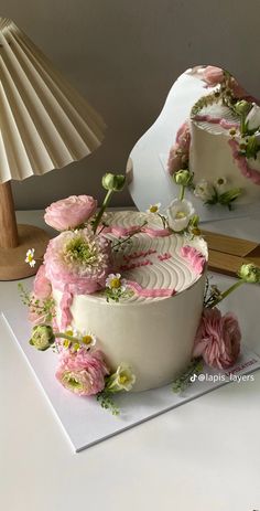 a white cake with pink and green flowers on it sitting in front of a mirror