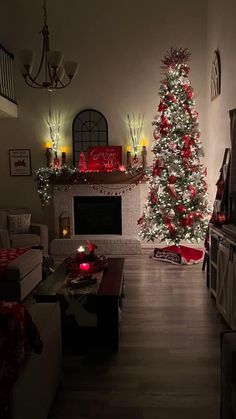 a living room decorated for christmas with a lit tree in the corner and stockings on the fireplace