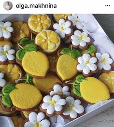 a box filled with yellow and white cookies covered in frosting next to small flowers