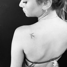 the back of a woman's neck with an arrow tattoo on her left shoulder