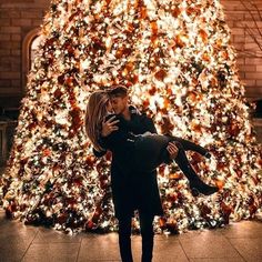 a man holding a woman in front of a christmas tree