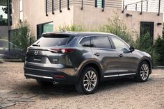 the rear end of a gray mazda cx - 9 parked in front of a building