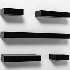 four black shelves on the wall with one empty shelf above them and two closed ones below it