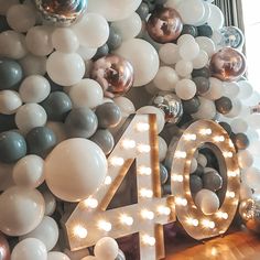 the balloons are all over the room and it is decorated with white, grey, and silver balloons