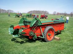 an orange and green farm tractor parked on top of a lush green field