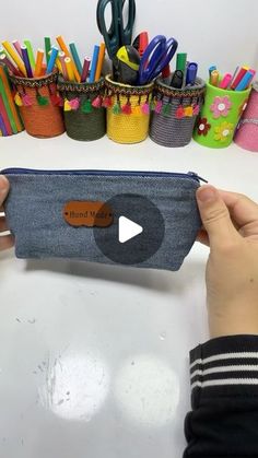 a person holding a pencil case in front of a bunch of pens