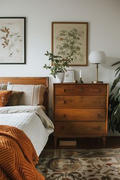 a bed room with a neatly made bed next to a wooden dresser and potted plant