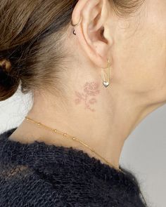 a woman with a small tattoo on her left side of her neck and behind her ear