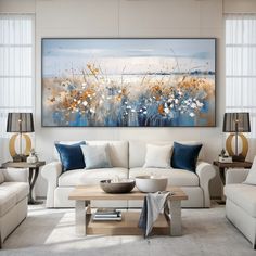 a living room with white furniture and blue accents on the painting above the couches