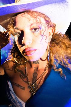 a woman wearing a white hat with tattoos on her chest