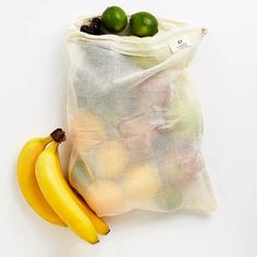 a bag full of fruit sitting next to two bananas