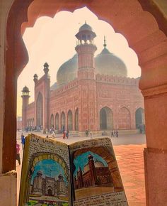 an open book sitting on top of a table in front of a building with arches