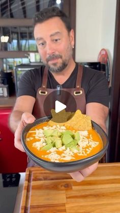 a man holding a bowl of food with guacamole and tortilla chips