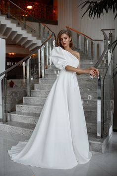 a woman in a white dress standing on some stairs