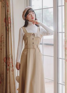 Midi pinafore dress with thick shoulder straps, button front, belted waist, side pockets and pleated skirt. Concealed back zipper. S: 33" chest, 27" waist, 42" lengthM: 34.5" chest, 28.5" waist, 42" lengthL: 36" chest, 30" waist, 42.5" lengthXL: 37.5" chest, 31.5" waist, 42.5" length Dresses Light Academia, Fitted Cottagecore Beige Midi Dress, Beige Full Skirt With Pleated Waist, Light Acadamia Dress, Academia Pinafore Dress, Light Academia Dress, Midi Pinafore Dress, Womens Winter Dresses, Tank Dresses