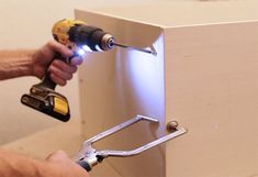 a man using a power drill to attach a cabinet