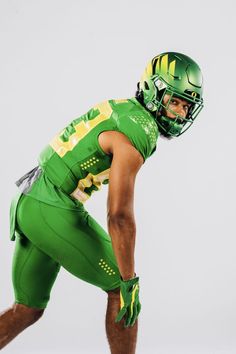 a football player in green and yellow is posing for the camera with his helmet on