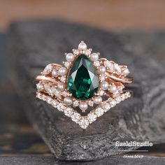 a close up view of a ring with pearls and an emerald gemstone in the center