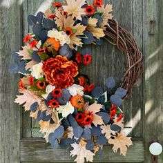 a wreath with flowers and leaves hanging on a door