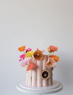 a pink cake decorated with flowers and fruit