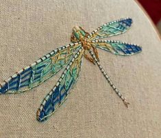 a close up of a dragonfly embroidered on a piece of fabric with beading