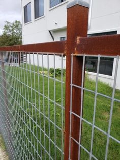 a close up of a metal fence on the side of a road near a building