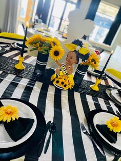 the table is set with sunflowers and black and white striped napkins, which have been placed on top of each other