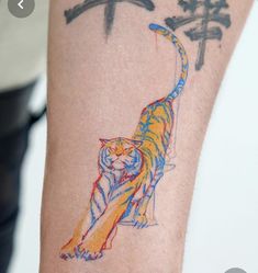 a colorful tiger tattoo on the arm of a person with chinese characters in the background