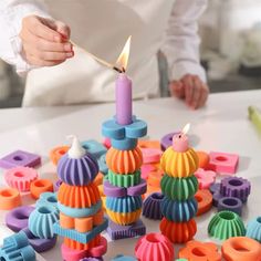 a person lighting a candle on top of colorful objects