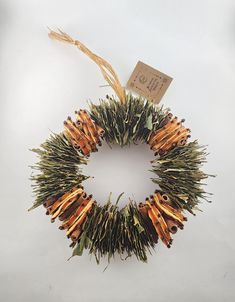 a wreath made out of sticks and dried grass with a tag hanging from the top