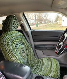 the interior of a car is covered in green crocheted blankets and sits next to a steering wheel